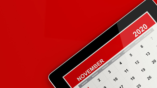 Red November smart tablet calendar on red background. Calendar and reminder concept. Horizontal composition with copy space.