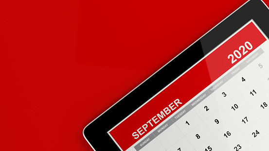 Red September smart tablet calendar on red background. Calendar and reminder concept. Horizontal composition with copy space.