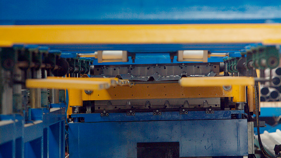 The industrial device for sheet metal bending by high precision metal sheet bending machine in factory. Line machine conveyor for cutting sheet metal in mechanical workshop. Close up. Selective focus.