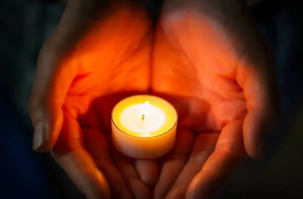 Photo of a small candle burning on the palm of its hand