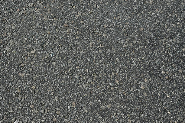 istock Asphalt roadway with uneven dark gray textured surface .Background 1196157281