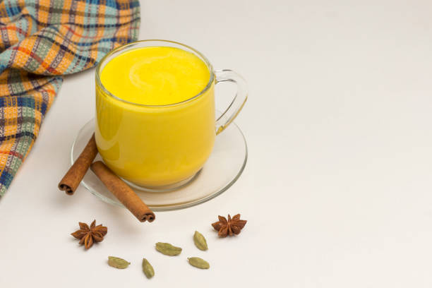 Golden latte on white background with ingredients for cooking Golden latte on white background with ingredients for cooking. Indian drink turmeric golden milk in glass. There is a place for text ayurveda cardamom star anise spice stock pictures, royalty-free photos & images