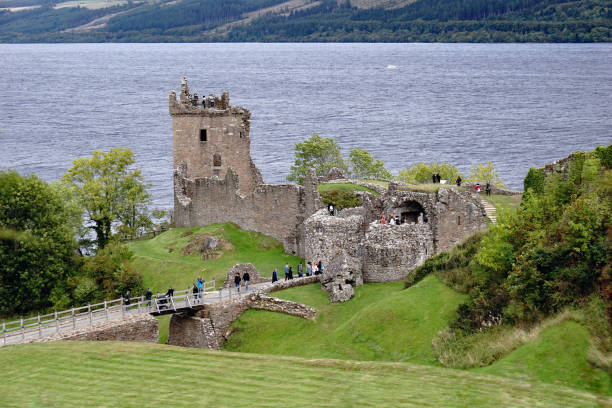 Tourists at Urquhart Castle by Loch Ness, Scotland Tourists at Urquhart Castle. The 13th century medieval castle located by the most famous lake in the world - Loch Ness. 15.09.2018, Drumnadrochit, Inverness, Scotland drumnadrochit stock pictures, royalty-free photos & images