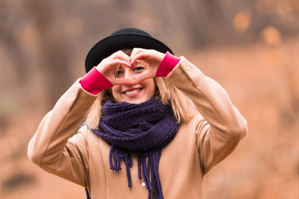 joven mujer al aire libre haciendo corazón - símbolo de forma para el amor y el romance. - heart shape loneliness women praying fotografías e imágenes de stock