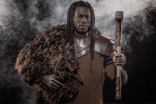 Portrait of a weapon wielding viking inspired black warrior in smoky studio shot