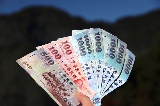 New Taiwan dollars currency - hand holding 100, 500 and 1000 NTD banknotes.