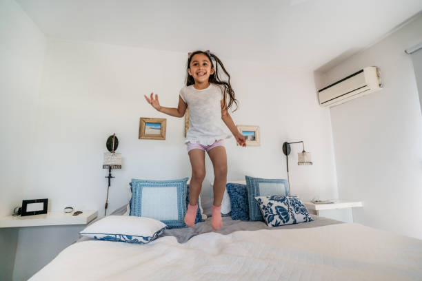 istock Happy girl jumping on bed 1196170822