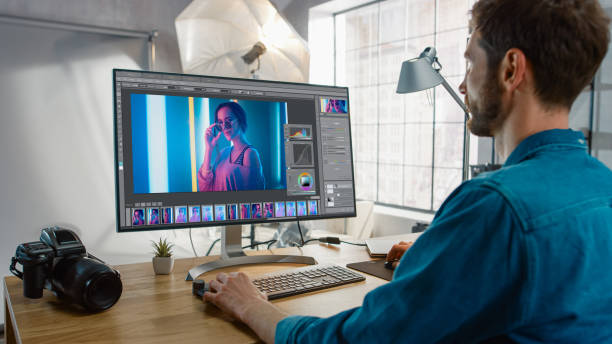 Professional Photographer Sitting at His Desk Uses Desktop Computer in a Photo Studio Retouches. After Photoshoot He Retouches Photographs of Beautiful Female Model in an Image Editing Software Professional Photographer Sitting at His Desk Uses Desktop Computer in a Photo Studio Retouches. After Photoshoot He Retouches Photographs of Beautiful Female Model in an Image Editing Software retouching stock pictures, royalty-free photos & images