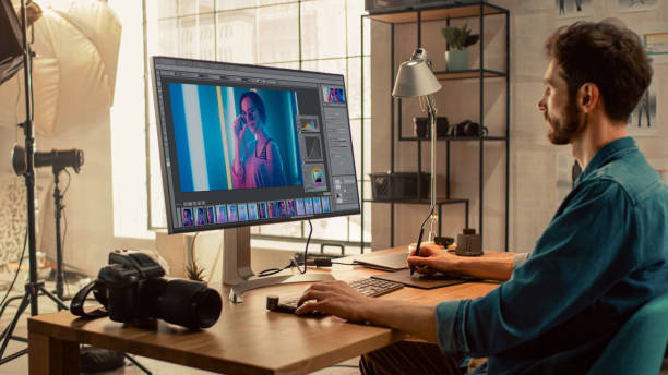 istock Professional Photographer Sitting at His Desk Uses Desktop Computer in a Photo Studio Retouches. After Photoshoot He Retouches Photographs of Beautiful Female Model in an Image Editing Software 1196171800