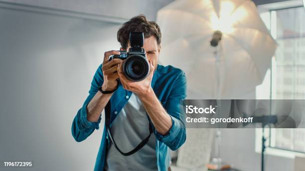In The Photo Studio With Professional Equipment Portrait Of The Famous Photographer Holding State Of The Art Camera Taking Pictures With Softboxes Flashing In Background Stock Photo - Download Image Now