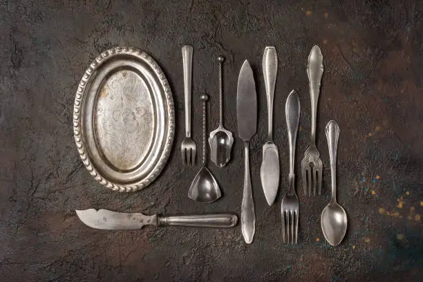 Top view of vintage silver cutlery or silverware on dark concrete background