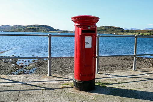 Old red royal mail post box at a seafront location in Scotland