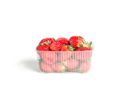 Fresh red strawberries in a plastic transparent container on white background
