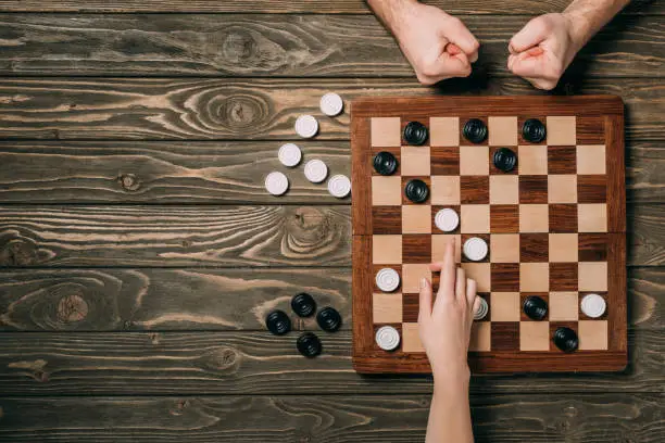 Photo of Cropped view of man and woman playing in checkers on wooden background