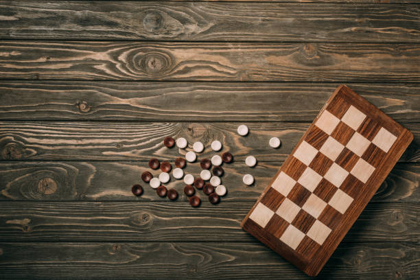 istock Top view of checkers and checkerboard on textured wooden surface 1196178801