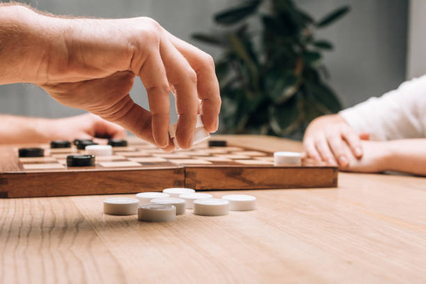 istock Side view of man holding white checkers while playing with woman at table 1196178826