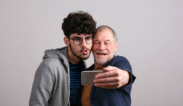 retrato de un padre mayor y un hijo pequeño en un estudio, tomándose selfie. - vertical caucasian glasses red hair fotografías e imágenes de stock