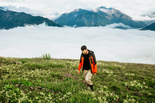 istock young man in red coat walking on clouds 1196187495