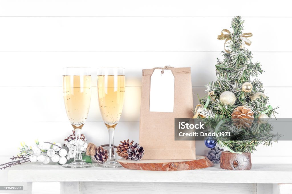 Wedding or Christmas Tag Mockap, Layout of a Wedding Tag on a Craft Bag with Christmas Tree Wedding or Christmas Tag Mockap, Layout of a Wedding Tag on a Craft Bag with Christmas Tree and Glasses of Champagne on a Light Background Bag Stock Photo