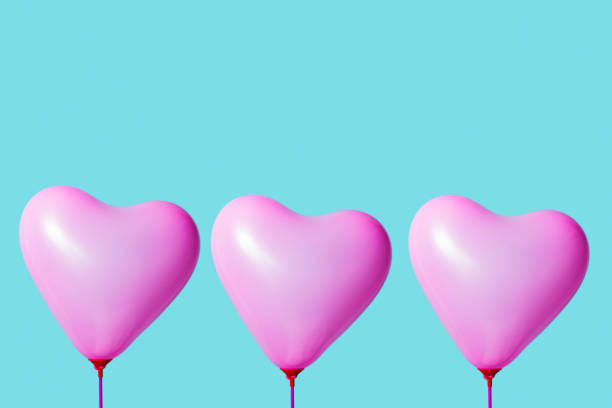 three pink heart-shaped balloons against a blue background with some blank space on top