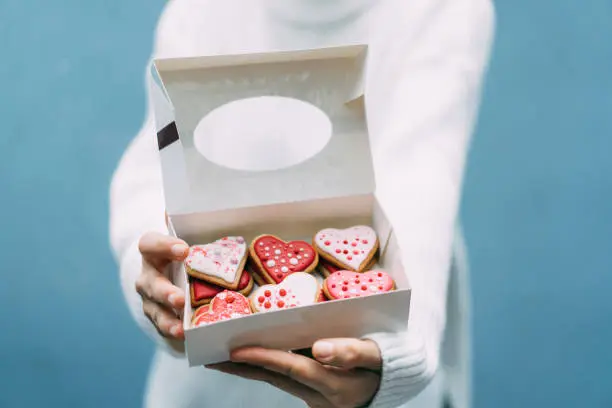 Photo of Woman holding box with Valentine's cookies