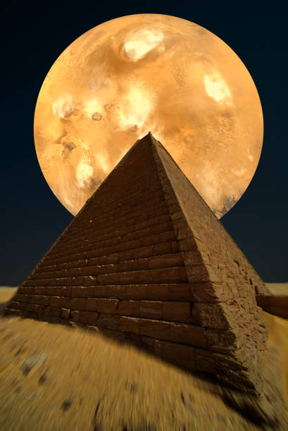 istock Shining planet behind a dark pyramid, sand in the foreground with artificial motion blur, pyramid from Sudan. Elements of this image furnished by NASA 1196198220
