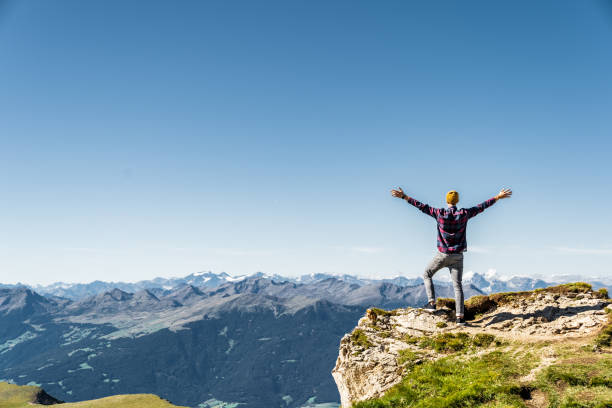 homme restant sur le bord de la roche avec les mains levées. alpes italiennes près de la ceceda. - european alps mountain mountain peak rock photos et images de collection