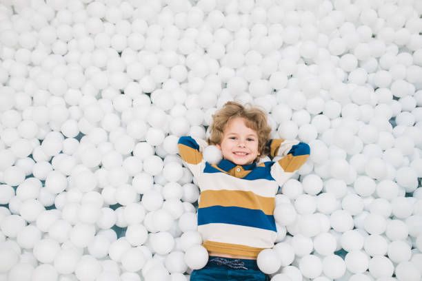 istock Adorable joyful little boy lying among white balloons and having fun 1196199543
