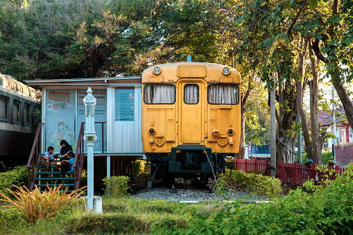 Hua Hin, Thailand - November 26th 2019 : Small library situated in a disused yellow train carriage, people sitting on the porch and stair