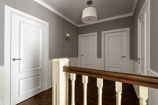 Interior of residential house. Hallway of second floor with several white doors. Home interior design in classic style.