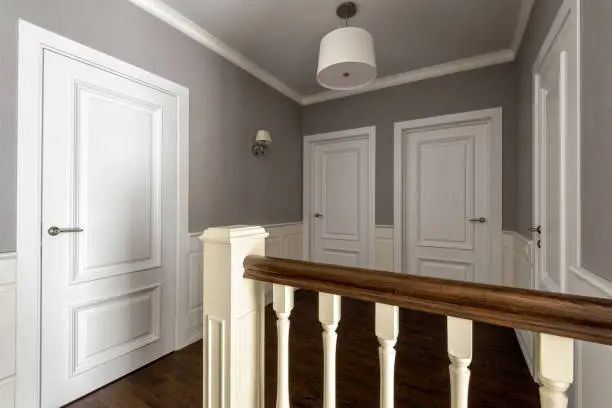 Photo of Interior of residential house. Hallway of second floor with several white doors.