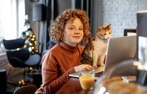 istock Young woman with cat using laptop 1196213307