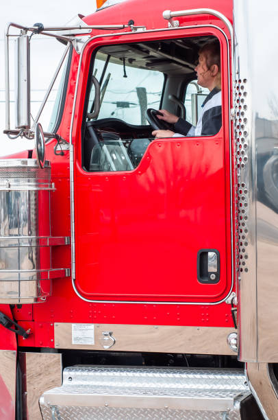 istock Woman Truck Driver looking out the windshield while driving a big rig 1196218162