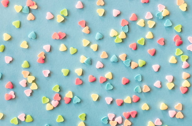 colorato cuore di zucchero a forma di cosparge cornice su sfondo blu verde. concetto di san valentino. - candy heart foto e immagini stock