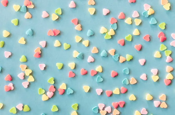 Photo of Colorful sugar heart shaped sprinkles frame on green blue background. Valentines day concept.