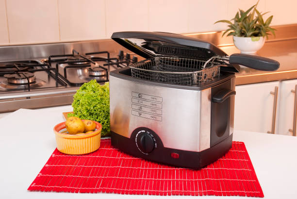 Electric frying pot; photo kitchen in the background. Electric frying pot; photo kitchen in the background. deep fryer stock pictures, royalty-free photos & images