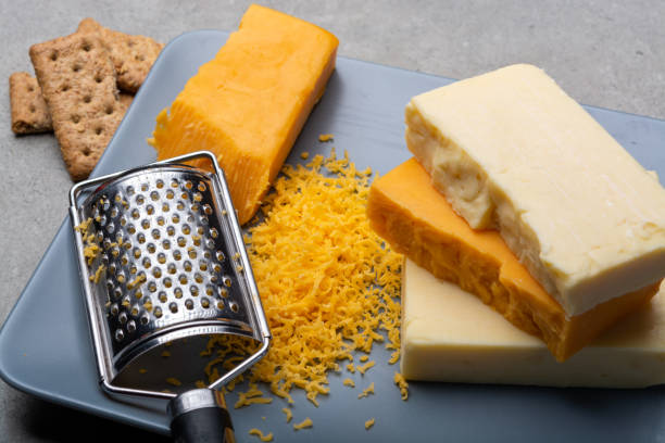 istock Cheese collection, matured and orange original British cheddar cheese in blocks and grated served on grey plate 1196238290