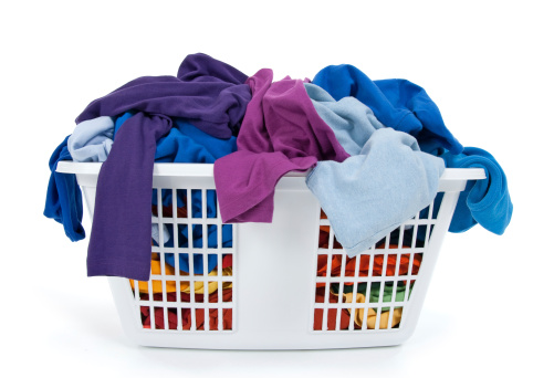 Colorful clothes in a laundry basket on white background. Blue, indigo, purple.