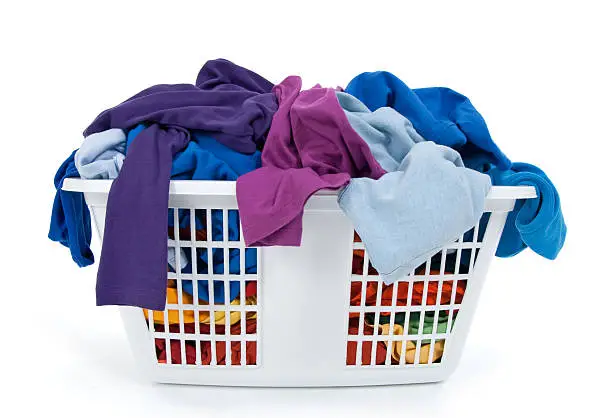 Photo of Colorful clothes in laundry basket. Blue, indigo, purple.