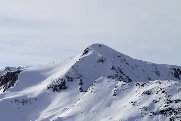 istock Snowy slope at high winter mountains and sunlit cloudy sky 1196240511