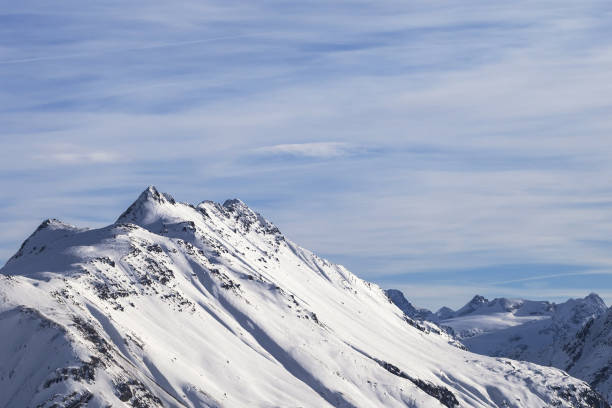 istock Snowy high winter mountains and beautiful cloudy sunlit sky 1196240519