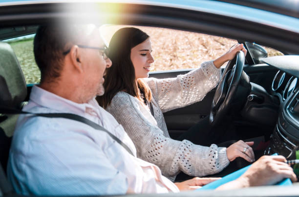 Teen girl on Driving test Driving male instructor taking notes on clipboard while sitting next to driving female teen student learning to drive on bright sunny day.Man tutor and teenage girl during driving class in the car driving test photos stock pictures, royalty-free photos & images