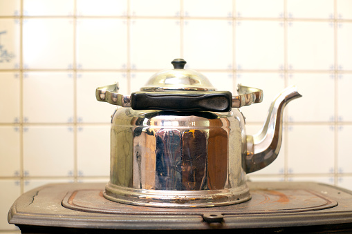 Old Kettle on the antique burning stove, vintage design used for a long time close-up