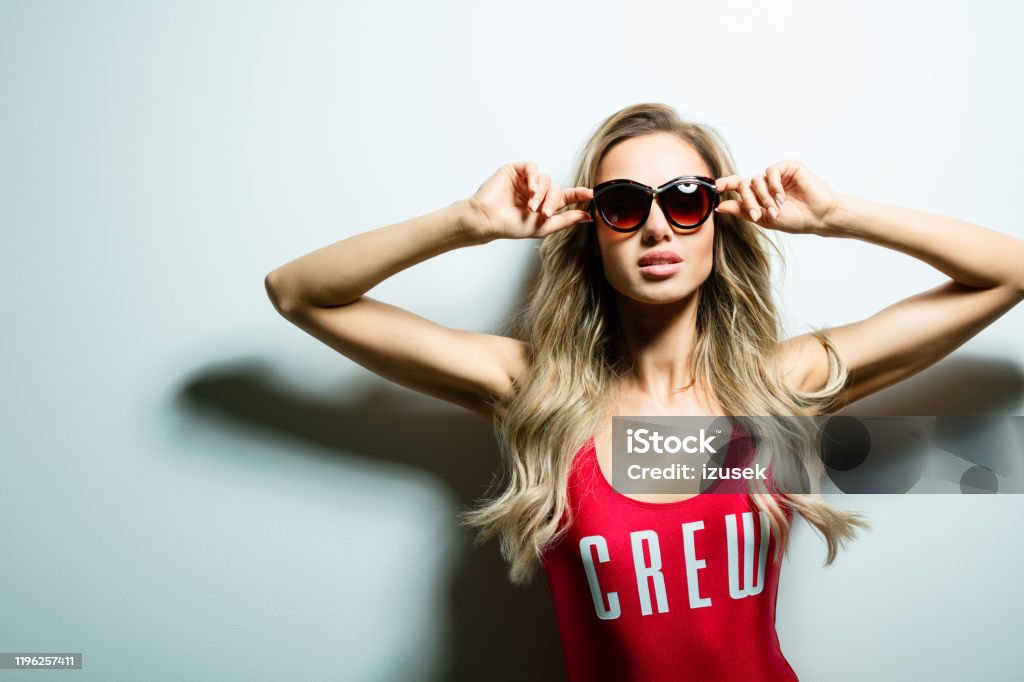 Summer poortrait Summer portrait of glamour blond long hair young woman wearing red swimsuit and dark sunglasses. Standing against white background. Studio shot, one person. 25-29 Years Stock Photo
