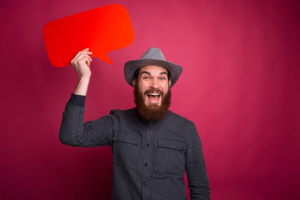 istock Happy young hipster man holding speech bubble 1196258236