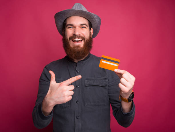 istock Cheerful young man pointing at yellow credit card 1196258237