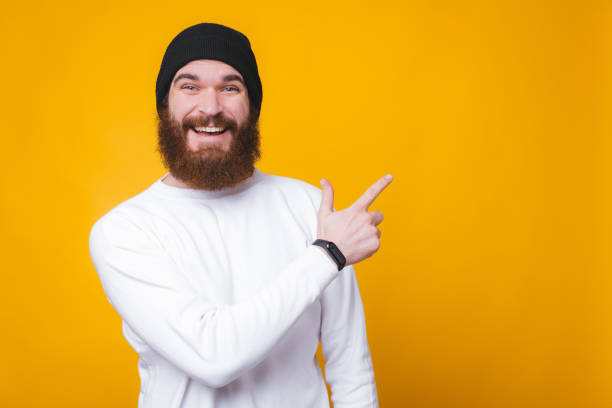 istock Cheerful happy man with beard pointing at copyspace 1196258544