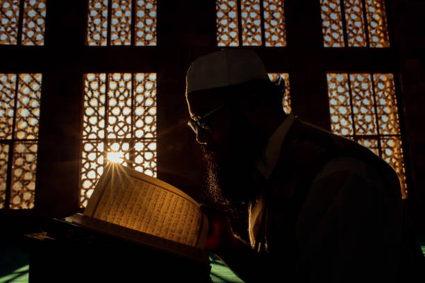 istock Young muslim man reading Koran in mosque 1196260448