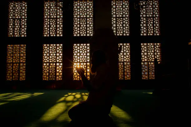 silhouette of a man worshiping in mosque