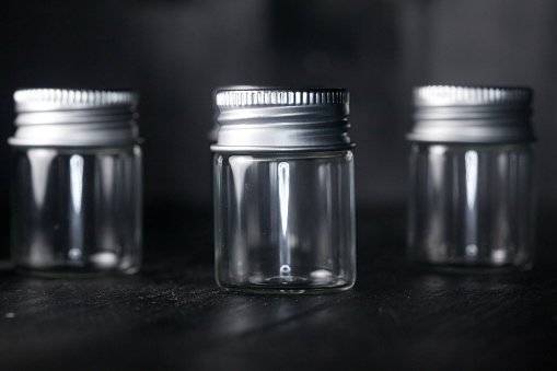 Four empty little jars on a black background